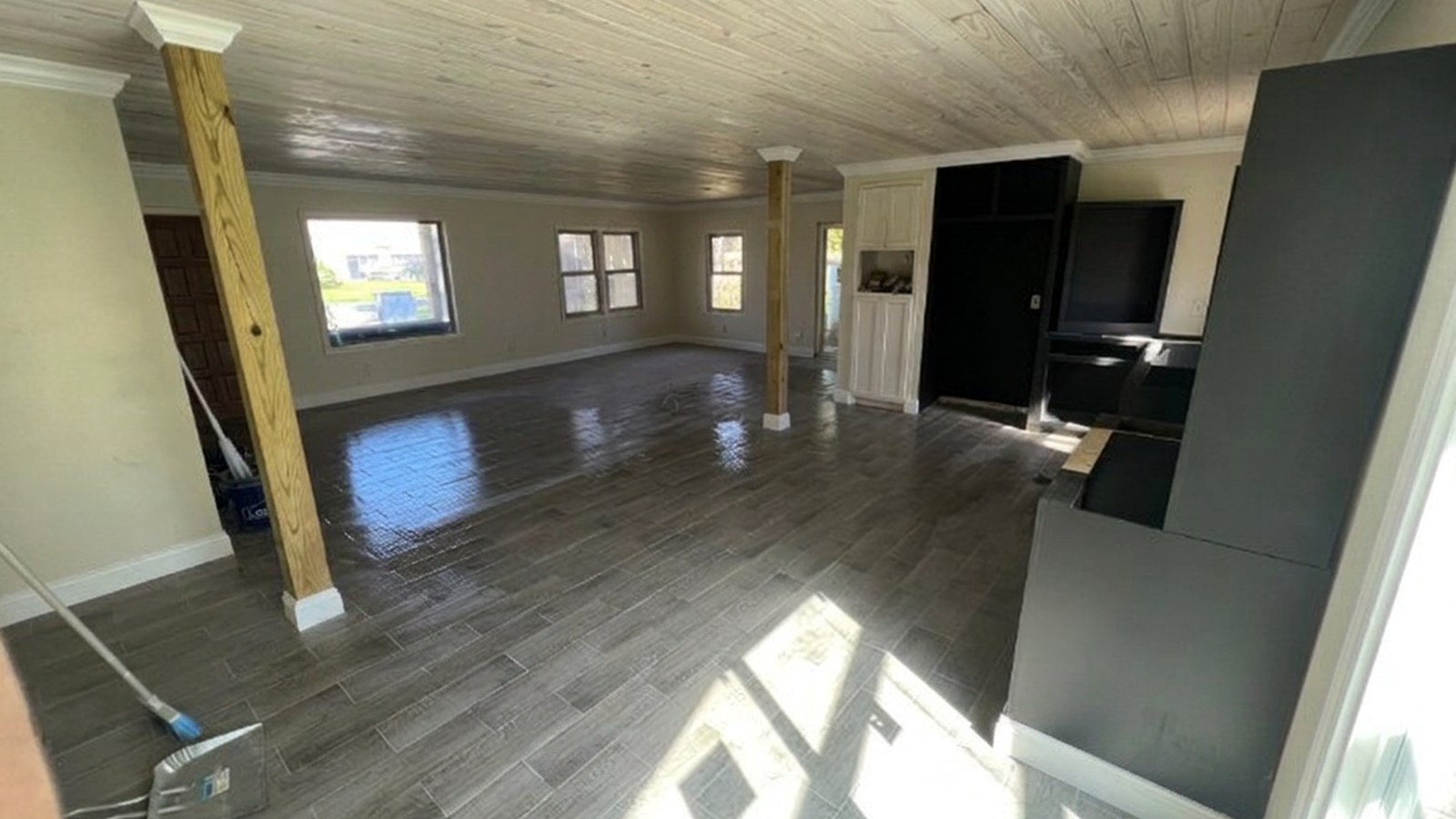 After — finished Waverly GA living area with white trim throughout Finished Waverly, GA open living area with wood plank ceiling, white baseboard and crown molding, and new plank flooring